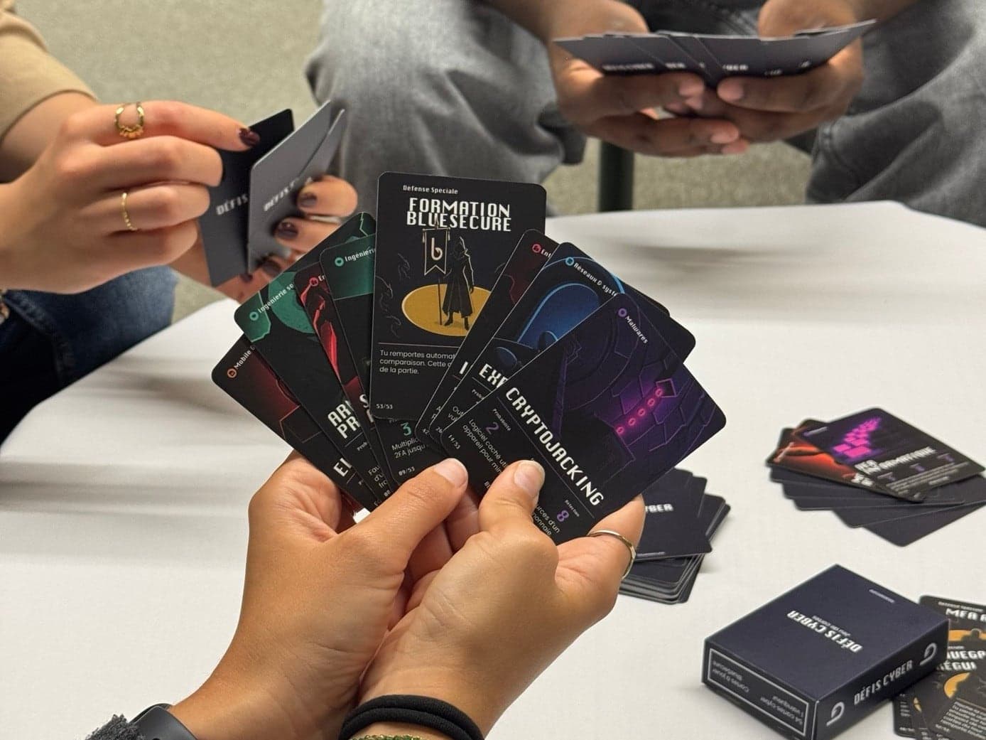 Joueurs tenant des cartes du jeu Défis Cyber autour d’une table